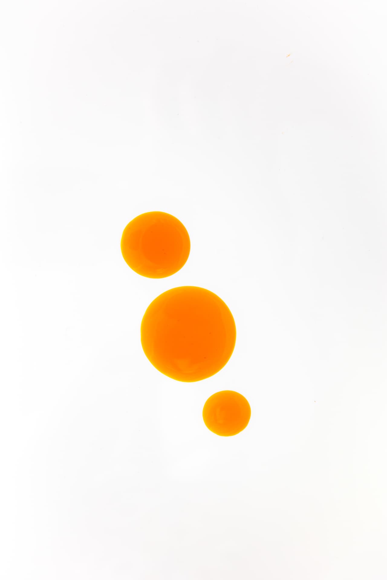 Orange oil droplets on a white surface, illustrating the formula’s botanical oils