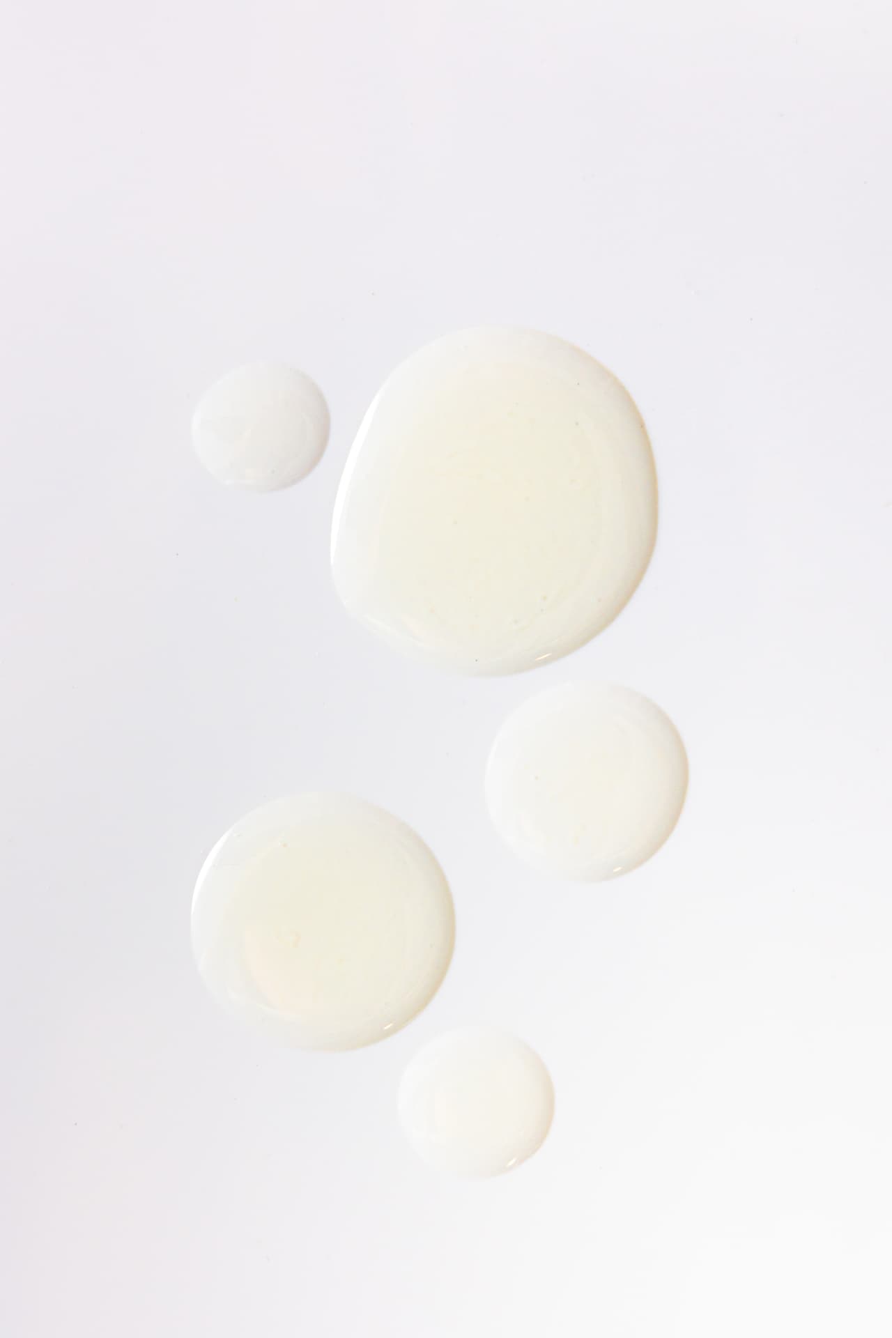 Light-colored oil droplets on a white surface, illustrating the formula’s oils